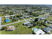 Aerial view of property featuring in-ground pool, screened-in enclosure, mature landscaping, and lush green lawn at 258 Shadow Nw St, Port Charlotte, FL 33952
