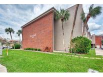 A view of the condominium building with well-maintained landscaping and several palm trees at 3100 Harbor Blvd # 116, Port Charlotte, FL 33952