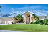 Tan house with metal roof, double door entry, and palm trees at 7369 Schefflera, Punta Gorda, FL 33955