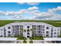 Aerial view of a modern apartment building with parking and tropical landscaping at 14131 Heritage Landing Blvd # 838, Punta Gorda, FL 33955