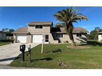 Tan two-story house with a two-car garage and palm tree at 240 Cicero Nw St, Port Charlotte, FL 33948