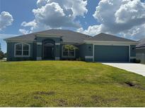 Charming single-story home featuring a lush green lawn and a two-car garage at 10133 Audrey St, Port Charlotte, FL 33981