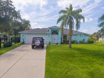 Cute light blue house with a palm tree and a spacious yard at 1355 Hempstead Ave, North Port, FL 34286