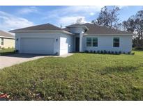 Single-story home with a two-car garage and landscaped lawn at 25126 Alcazar Dr, Punta Gorda, FL 33955