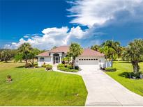 Single-story home with attached garage, lush landscaping, and terracotta roof at 16407 San Edmundo Rd, Punta Gorda, FL 33955