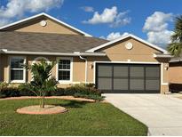 Tan house with gray garage door and landscaping at 25168 E Lenox Cir, Punta Gorda, FL 33950