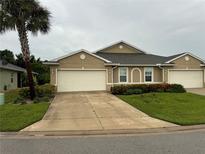 Tan two-car garage home with landscaping and a palm tree at 7633 W Lenox Cir, Punta Gorda, FL 33950
