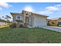 Well-maintained single-story home with a two-car garage and green lawn at 4255 Oak Terrace Cir, Port Charlotte, FL 33953