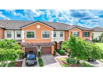 Two story townhome with orange exterior, two car garage, and landscaped front yard at 20149 Lagente Cir, Venice, FL 34293