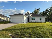 White house with a two-car garage and a well-manicured lawn at 25245 Delgado Dr, Punta Gorda, FL 33955