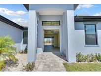 Inviting entryway to light blue home with a paved walkway leading to the front door at 13164 Amaryllis Cir, Port Charlotte, FL 33981