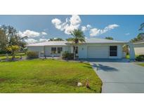 Single-story home with metal roof, attached garage, and well-maintained lawn at 22465 Vale Ave, Punta Gorda, FL 33980