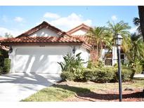 Charming home showcasing a red tile roof, two-car garage, and tropical landscaping at 956 Harbor Town Dr, Venice, FL 34292