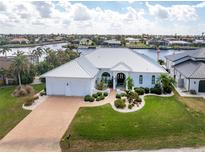 Luxury waterfront home with a metal roof, spacious driveway, and lush landscaping at 1945 Jamaica Way, Punta Gorda, FL 33950
