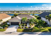 Single-story home with a landscaped yard and two-car garage, located on a canal at 24080 Buckingham Way, Punta Gorda, FL 33980