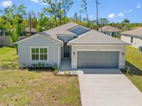 Exterior view of a single-Gathering home featuring a two-car garage and landscaping at 1301 Preston St, Port Charlotte, FL 33952