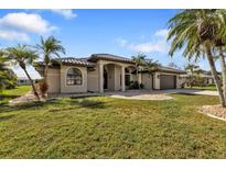 Single-story home with tile roof, palm trees, and a well-manicured lawn at 25373 Tether Ln, Punta Gorda, FL 33983