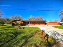 Front view of a single story home with a large yard, driveway, and detached garage at 301 Country Club Way, Venice, FL 34285