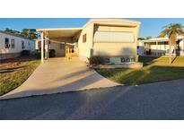 Charming mobile home features a covered parking area and well-maintained lawn with landscaped details at 5524 Holiday Park Blvd, North Port, FL 34287