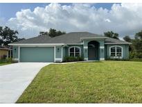 Charming single-story home with a well-manicured lawn, attached two-car garage, and light blue exterior at 27462 Pasto Dr, Punta Gorda, FL 33983