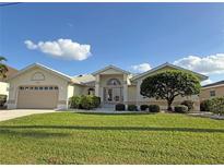 Tan house with two-car garage, lush lawn, and landscaping at 1375 Grebe Dr, Punta Gorda, FL 33950