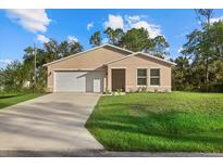 Tan house with white garage door and green lawn at 14220 Dunlap Ave, Port Charlotte, FL 33953