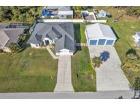 Aerial view of a home with a large garage, concrete driveway, and well-maintained lawn at 17152 Wintergarden Ave, Port Charlotte, FL 33948