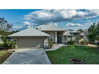 Single-story home with metal roof, attached garage, and landscaped yard at 2578 Broad Ranch Dr, Port Charlotte, FL 33948