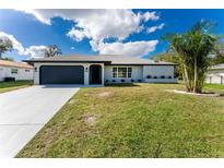 Newly renovated home with gray garage door and landscaped yard at 1239 Ramsdel St, Port Charlotte, FL 33952