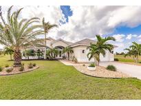 Tan house exterior with palm trees, landscaping, and a paved driveway at 24479 Tia Ct, Punta Gorda, FL 33955