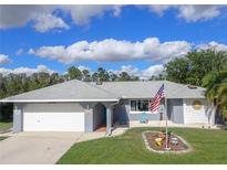Single-story home with gray exterior, white garage, and American flag at 26352 Copiapo Cir, Punta Gorda, FL 33983