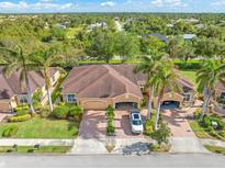 Aerial view of single-Gathering home with two-car garage, lush landscaping, and palm trees at 4410 Turnberry Cir, North Port, FL 34288