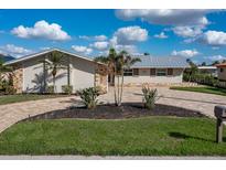 Single-story home with a circular driveway, metal roof and landscaping at 440 Norma Ct, Punta Gorda, FL 33950