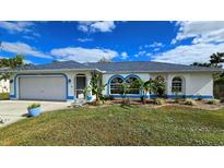 Single-story home with a gray roof, white walls, and blue accents at 1370 Kenmore St, Port Charlotte, FL 33952