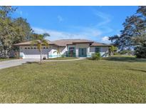 Charming single-story home with well-manicured lawn, blue trim, and a two-car garage at 182 Santarem Cir, Punta Gorda, FL 33983