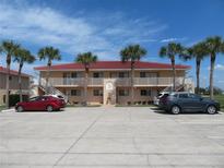 Two-story condo building with red tile roofs, palm trees, and ample parking at 1360 Rio De Janeiro Ave # 117, Punta Gorda, FL 33983