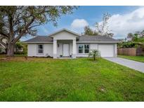 Charming single-story home featuring a well-maintained lawn, attached garage, and inviting front entrance at 2190 Taunt St, Port Charlotte, FL 33948