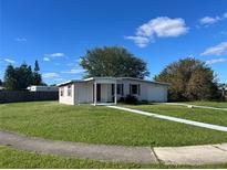 Ranch style home with a large yard, driveway, and mature trees at 2273 Ednor St, Port Charlotte, FL 33952