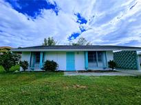 Charming single-story home with a teal door and well-manicured lawn at 683 W Tarpon Nw Blvd, Port Charlotte, FL 33952