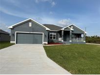 Charming single-story home with well-maintained lawn, covered porch, and gray color palette at 14154 Baracoa Ln, Port Charlotte, FL 33981