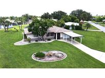 Single-story home with carport, mature landscaping, and large grassy yard at 112 Sunnyside Nw St, Port Charlotte, FL 33952