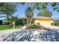 Beautiful yellow house with a well-manicured lawn and driveway at 6510 Kimlinda Ln, Sarasota, FL 34243