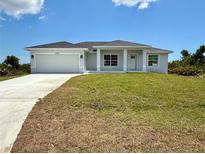 Beautiful single-story home features a two-car garage, well-manicured lawn, and light blue exterior paint at 13541 Jeronimo Ln, Port Charlotte, FL 33981