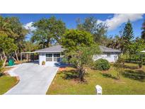 Single-story home with gray exterior, carport, and nicely landscaped yard at 14454 Nw Chamberlain Blvd, Port Charlotte, FL 33953