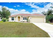 Tan one-story house with a two-car garage and landscaped yard at 3208 Congress St, North Port, FL 34288