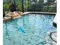 Sparkling in-ground pool with waterfall feature and screened enclosure overlooking lush landscaping at 1196 Hinton St, Port Charlotte, FL 33952