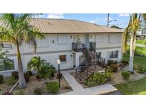 Two-story building with light-colored exterior, stairs, and landscaping at 26485 Rampart Blvd # E7, Punta Gorda, FL 33983