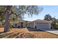 Charming single-story home with a well-manicured lawn, mature tree, and a two-car garage at 1451 Glenview Rd, North Port, FL 34288