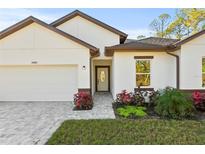 White house with brown roof, paver driveway, and landscaping at 14059 Gailwood Ave, Port Charlotte, FL 33953