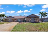 Tan house with stone accents, a spacious driveway, and palm trees in the front yard at 3310 Middletown St, Port Charlotte, FL 33952